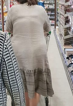 Two elderly women with a shopping cart of Caucasian appearance in a supermarket, back view, vertical, close-up.