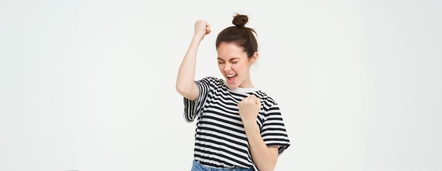 Portrait of happy woman winning, celebrating victory, rooting for team, triumphing, standing over white background.