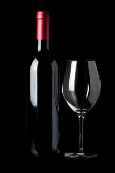 Bottle of red wine and a wine glass insulated against a black background