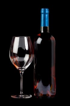 Bottle of rosé wine and an empty wine glass against a black background