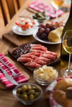 Full table of prosciutto, olives, cheese, salad and wine