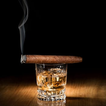 Whiskey and cigar on wooden background close up