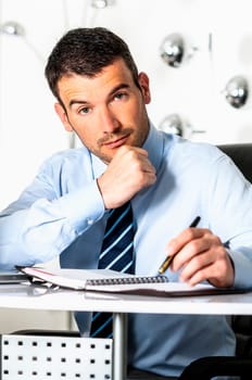 An attractive business man is writing on a paper