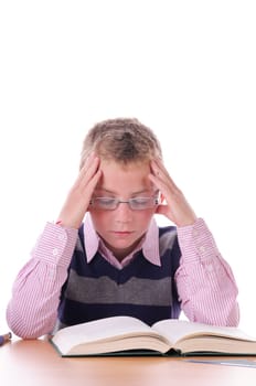 A blond teenage boy with glasses wears a ringed sweater. He sits at his desk and reads strained in a book,exposed against a white background.