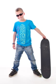 Teenage boy wears a blue T-shirt and cool sunglasses and poses with his skateboard,isolated against a white background.