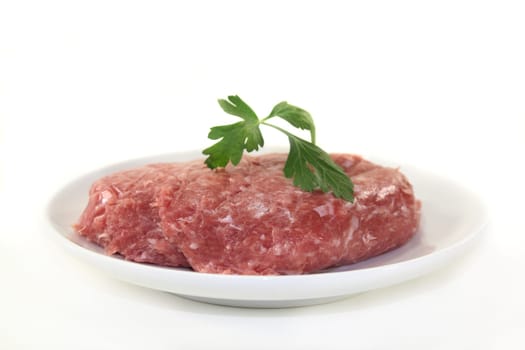 raw minced meat and parsley on a white plate