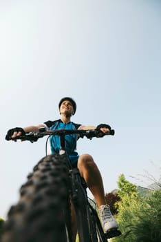 young woman training on mountain bike and cycling in park. Copy space, low angle view