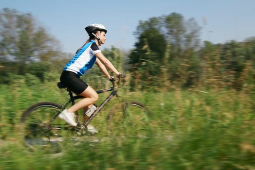 young woman training on mountain bike and cycling in park. Panning technique with motion blurred foreground