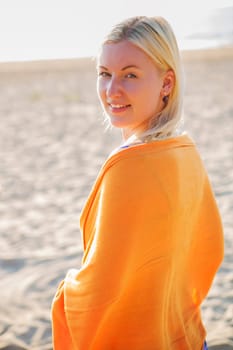 Woman coated in orange scarf standing on beach