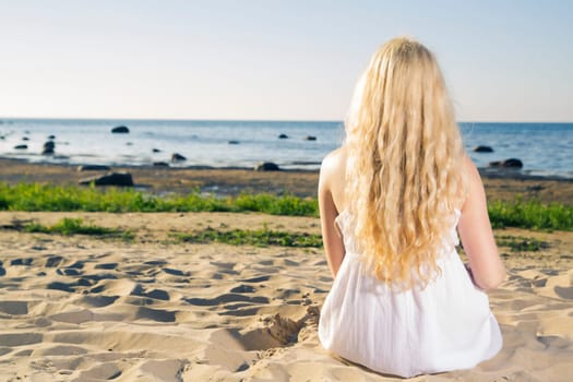 Dreaming woman in white dress on warm beach