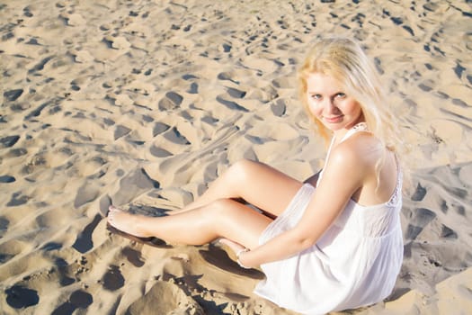 Woman in white dress posing on cool sand