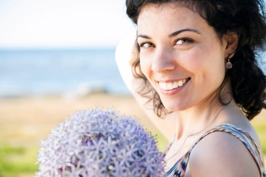 Happy woman with dark hairs posing with flower