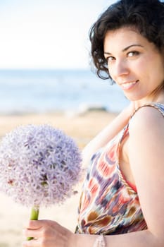 Smiling woman with dark hairs posing with flower