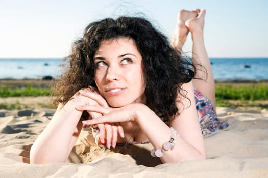 Dreaming woman with dark hairs lying at beach