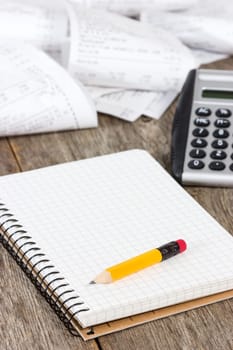 Calculating expenses. Spiral notebook, calculator and grocery shopping receipts