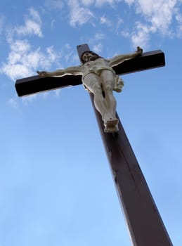 Wooden cross with Jesus Christ with blue sky in background