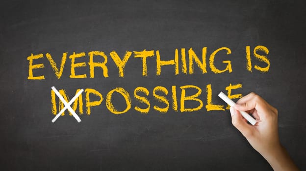 A person drawing and pointing at a Everything is Possible Chalk drawing