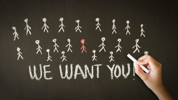 A person drawing and pointing at a We want you chalk drawing