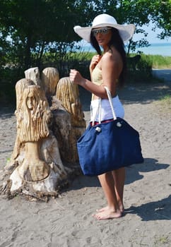 A young pretty teenager girl with a white sun hat and blue back is walking.to the beach for a nice sunbath..