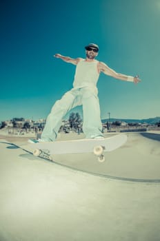Skateboarder in a concrete pool at skatepark on a sunny day.