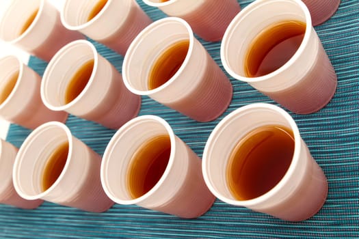 Lots of disposable cups with tea on a colorful background.