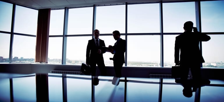 Business people spending a usual busy day in office, only silhouettes being recognizable