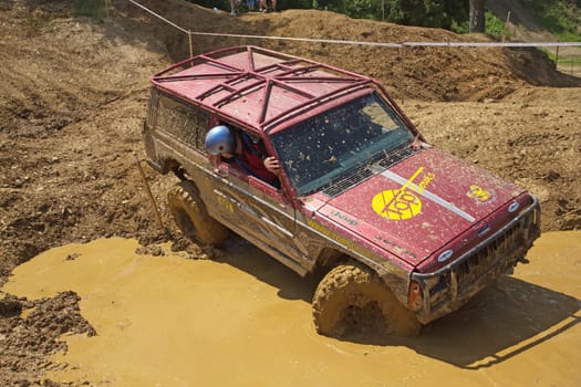 MOHELNICE, CZECH REPUBLIC - JUNE 09. Red off road car passing in muddy puddles on the "BIG SHOCK CUP Trial 2013"" on June 09, 2013  in the town of Mohelnice, Czech Republic."