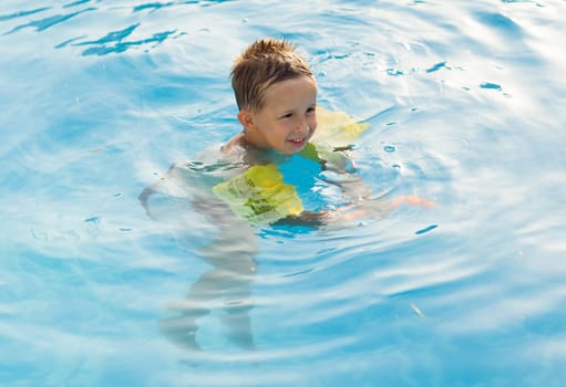 Happy girl with goggles relaxing in swimming pool