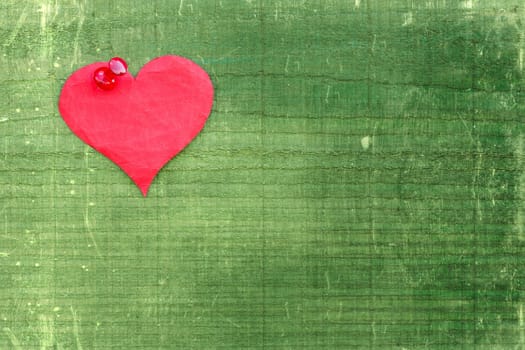 Paper heart pinned to the green wooden wall