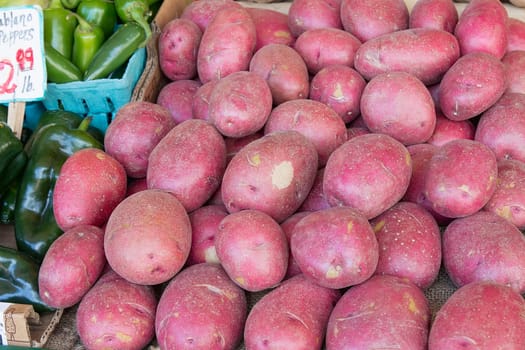 Red Skin Potatoes Display next to Chili Peppers at Farmers Market Fruits and Vegetables Stall