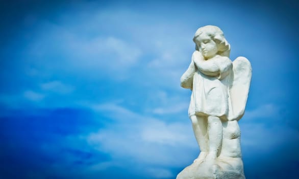 Praying sculpture angel on cloud background.