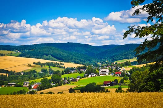 Countryside village surrounded by mountains, fields and forest.