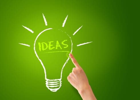A Hand pointing of a Ideas Lightbulb on green background.
