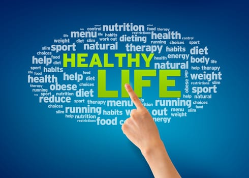 Hand pointing at a Healthy Life word cloud on blue background.
