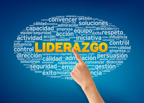 Hand pointing at a Liderazgo word cloud on blue background.