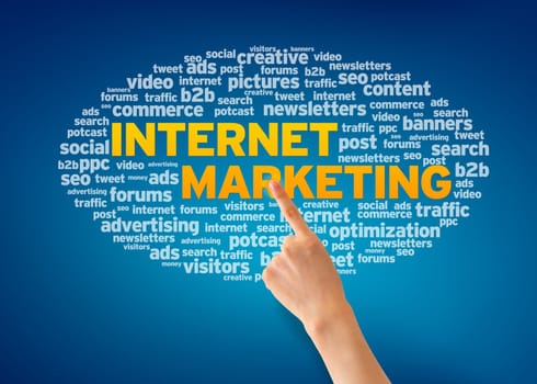 Hand pointing at an Internet Marketing word cloud on blue background.