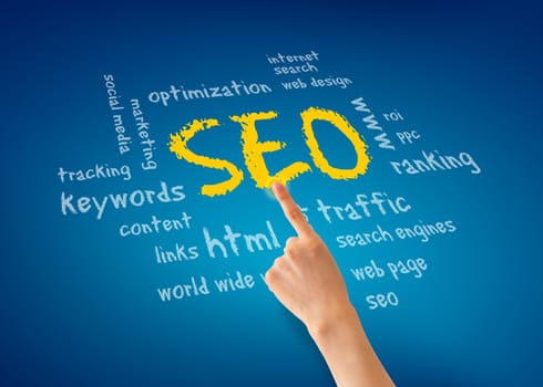 Hand pointing at a SEO illustration on blue background.