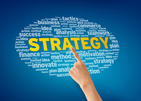 Hand pointing at a Strategy Word Cloud on blue background.