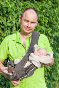 Father carrying son in sling outdoor