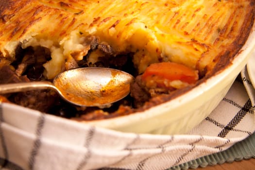 A delicious home made meat pie on a wooden table that makes your mouth water.
