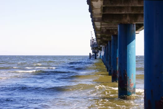 The photograph of pillars in the sea under a bridge.