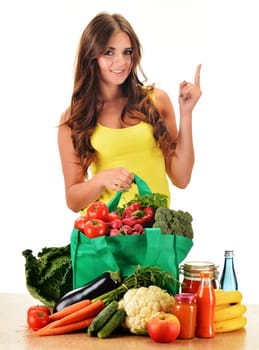 Young woman with variety of grocery products in shopping bag isolated on white
