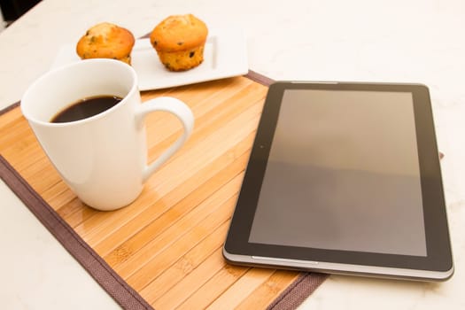 Vanilla with chocolate chips Muffins with  a cup of coffee meanwhile using the tablet..