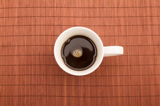 A steamy cup of coffee on a placemat.