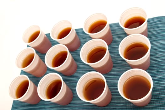 Lots of disposable cups with tea on a colorful background.