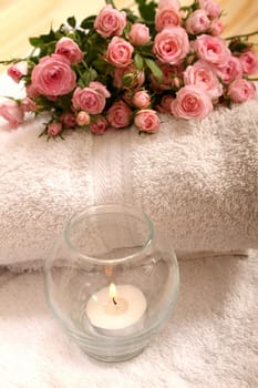 Bunch of small pink Roses on towels with candle, close up..