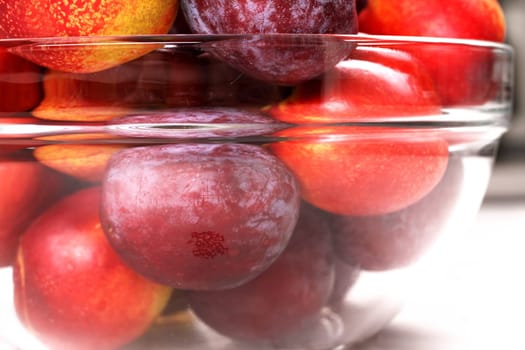 Nectarines and Plums in a glass bowl, close up.