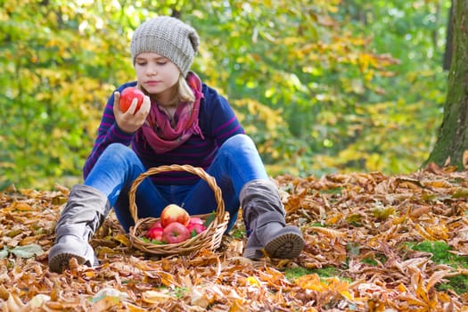 young girl with basket of apples in autumn garden