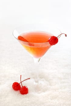 Cherry cocktail in a martini glass decorated with maraschino cherries, on snow.
