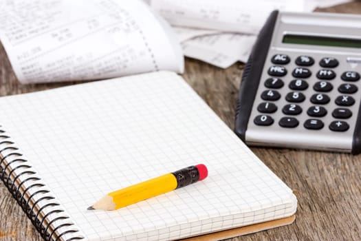 Spiral notebook, pencil,calculator and grocery shopping receipts